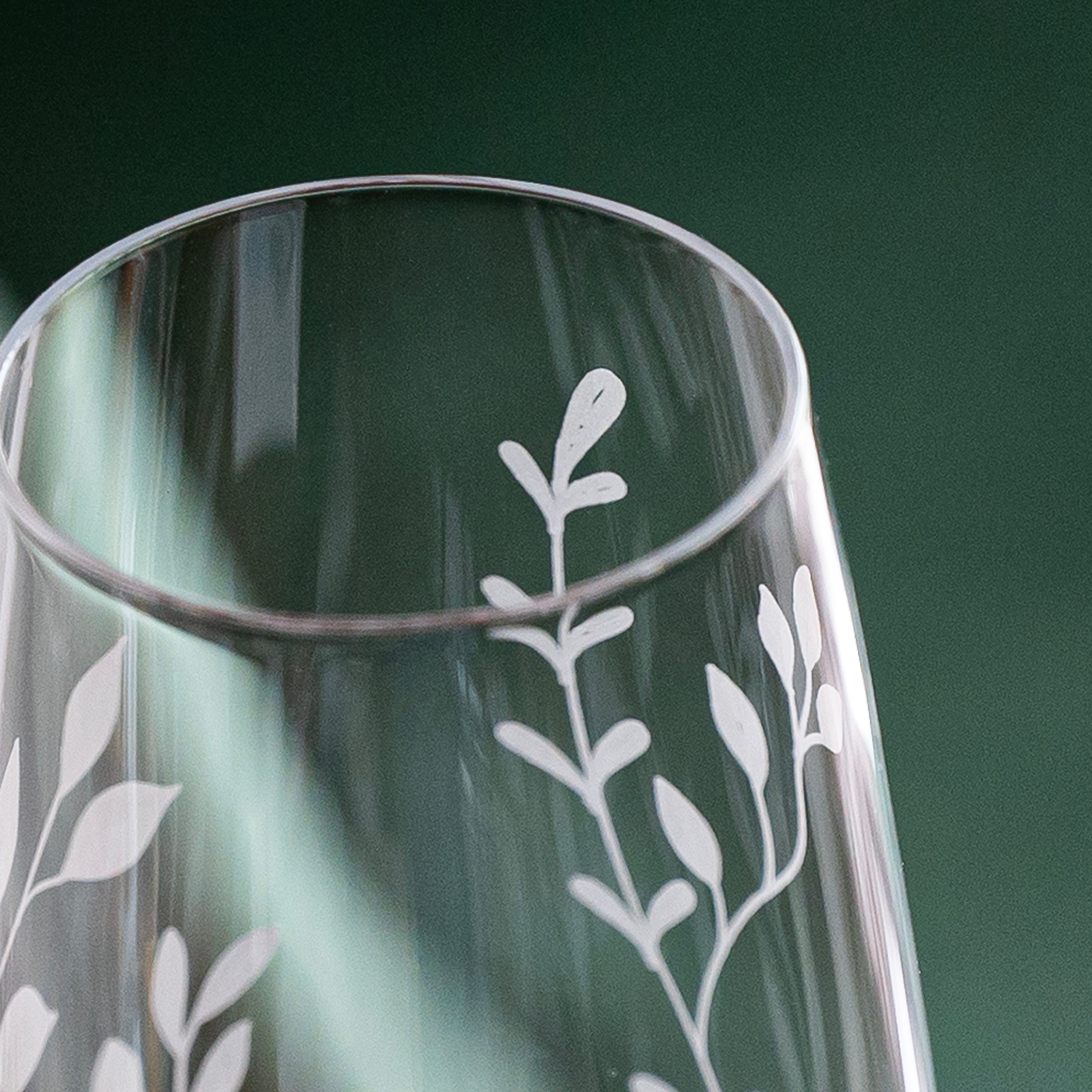 Clear glass vase with white leaf patterns on a green background