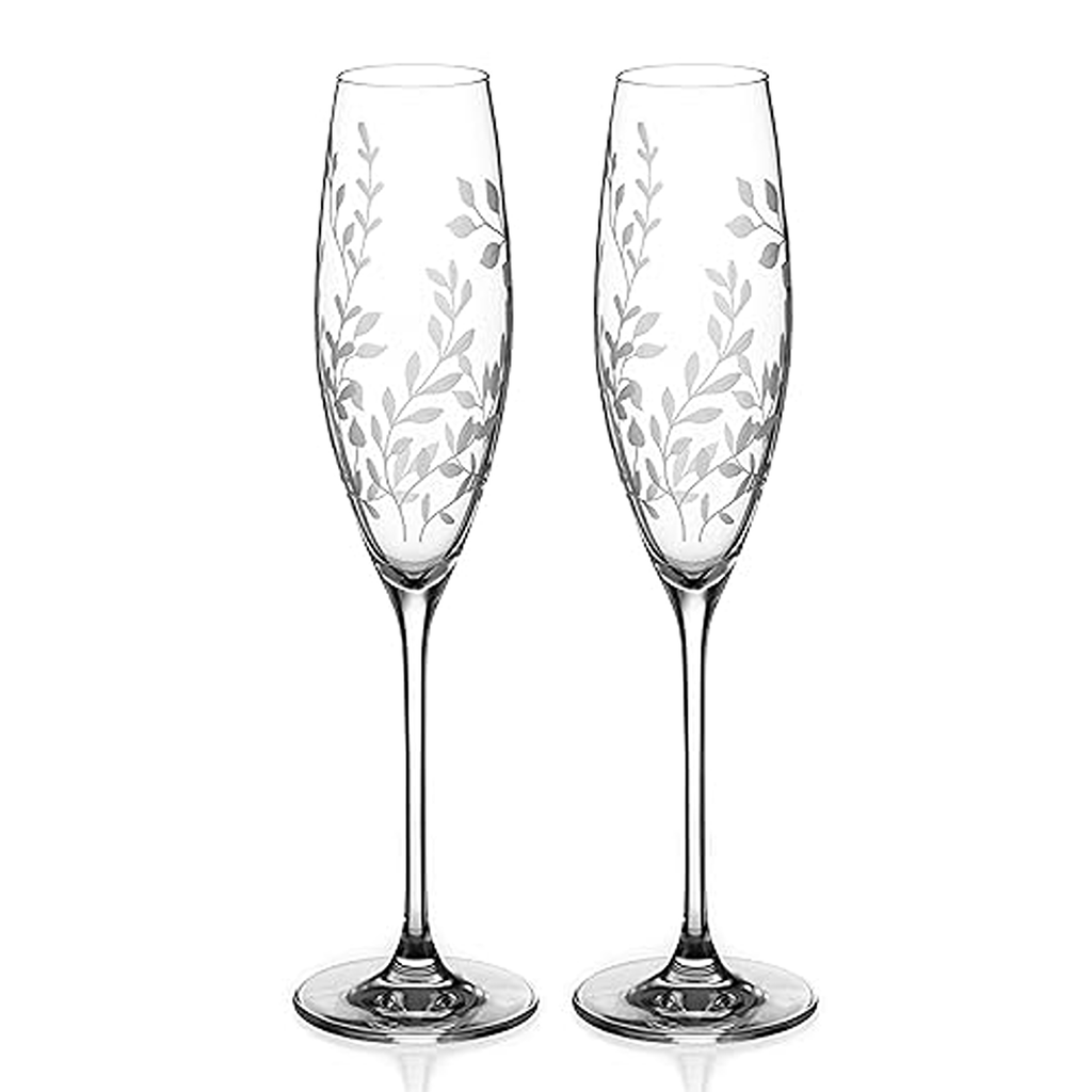 Two elegant champagne flutes with leaf patterns on a white background