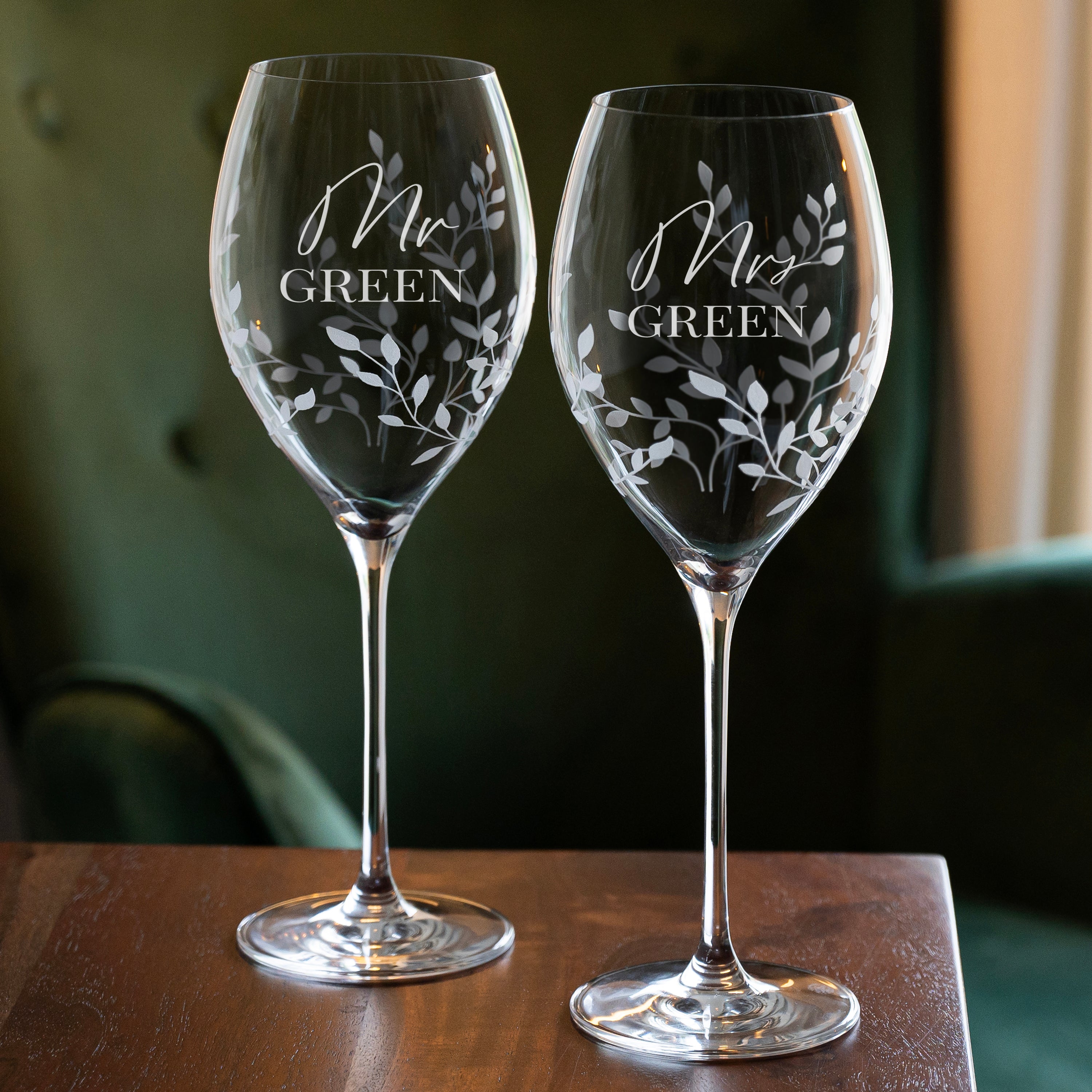 Two etched wine glasses with 'Mr Green' and 'Mrs Green' text on a wooden surface.