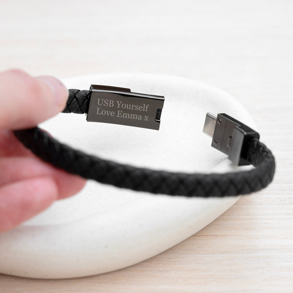 Black braided USB cable with engraved text held by a hand on a white background