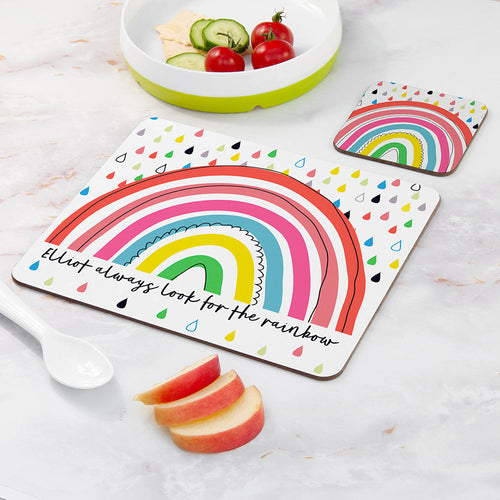 Colorful rainbow placemat with text on a table with fruit and a bowl.