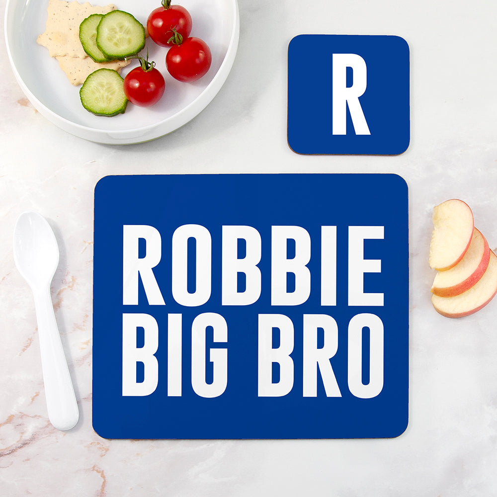 Blue placemat with 'ROBBIE BIG BRO' text on a table with food.