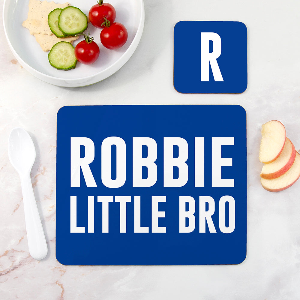Blue placemat with 'ROBBIE LITTLE BRO' text on a marble surface with food items.