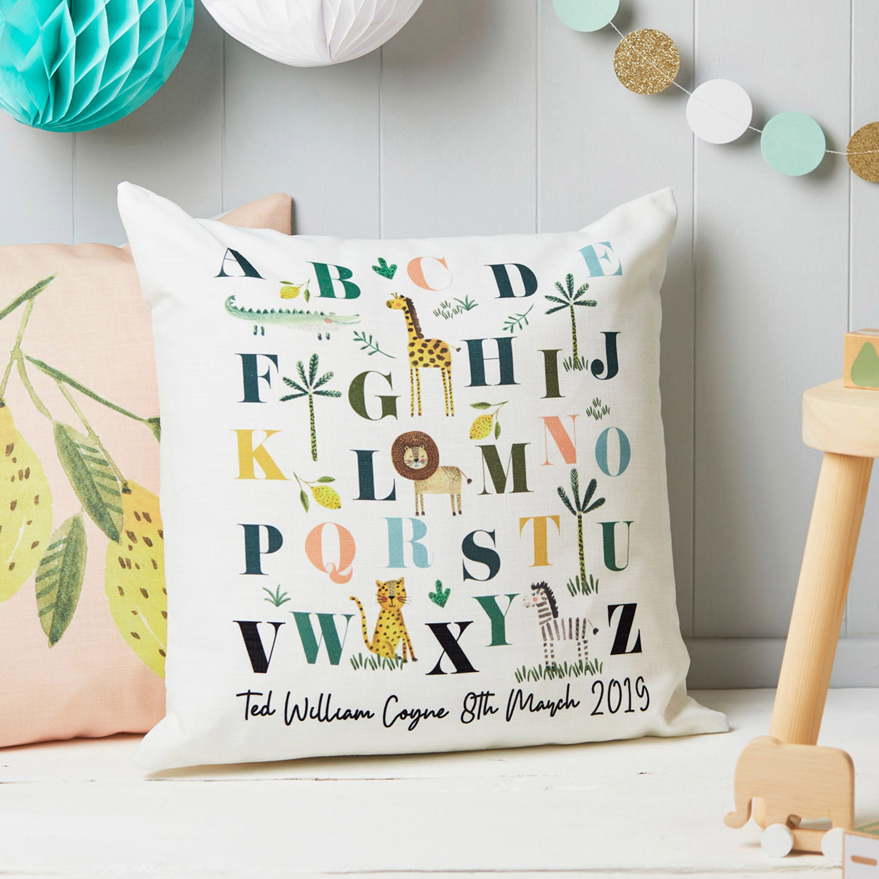 Decorative pillow with alphabet design and personalized text in a child's room.