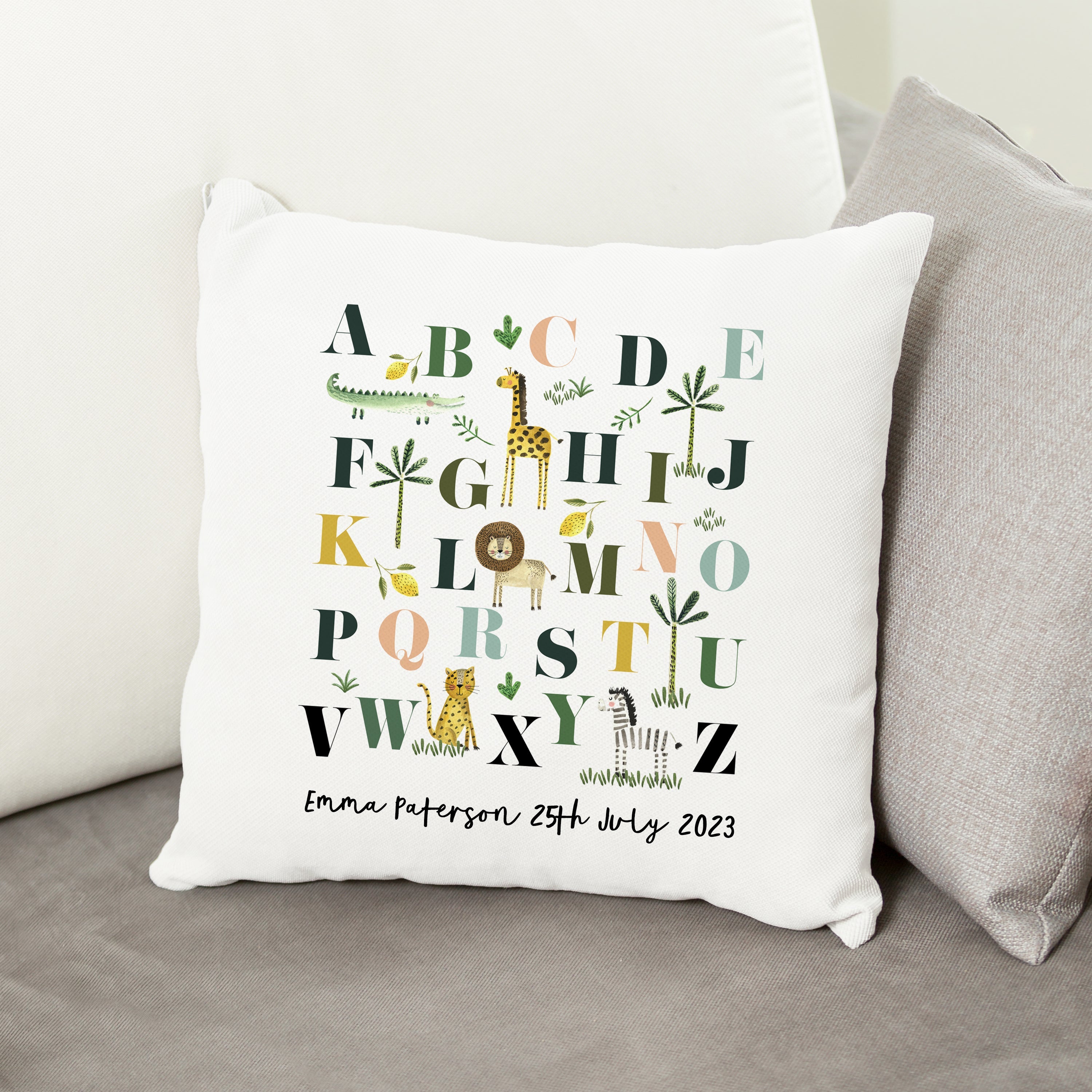 Decorative pillow with alphabet design and personalized text on a couch.