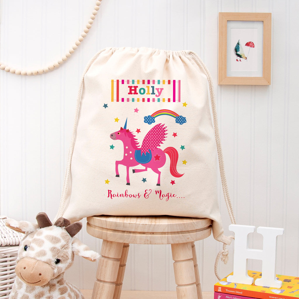 Drawstring bag with unicorn design and 'Holly' text on a wooden stool against a white wall.
