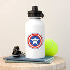 White water bottle with superhero emblem and 'Oscar' text, next to a tennis ball on a wooden surface.