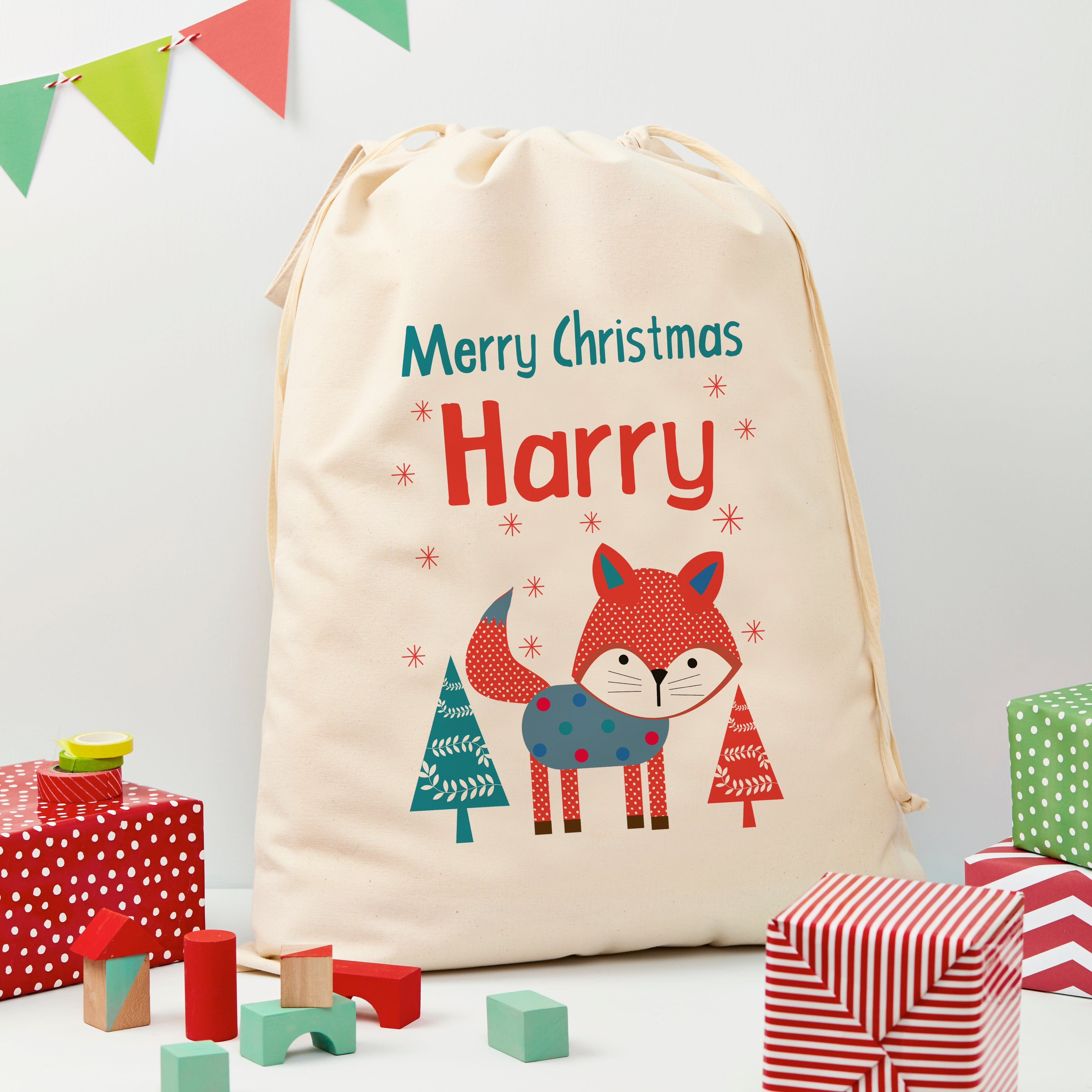Personalized Christmas drawstring bag with a fox design and 'Merry Christmas Harry' text, surrounded by festive items.