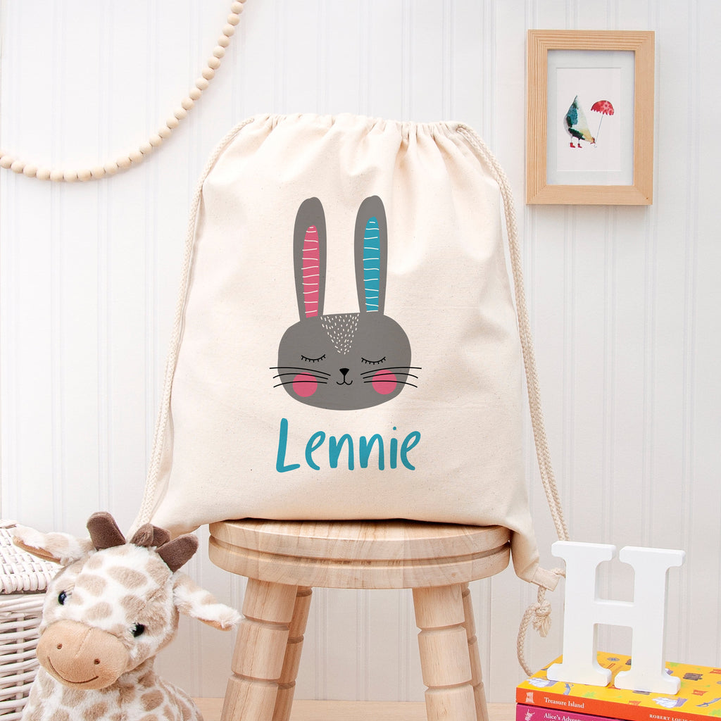 Drawstring bag with a rabbit design and 'Lennie' text on a wooden stool against a white wall.
