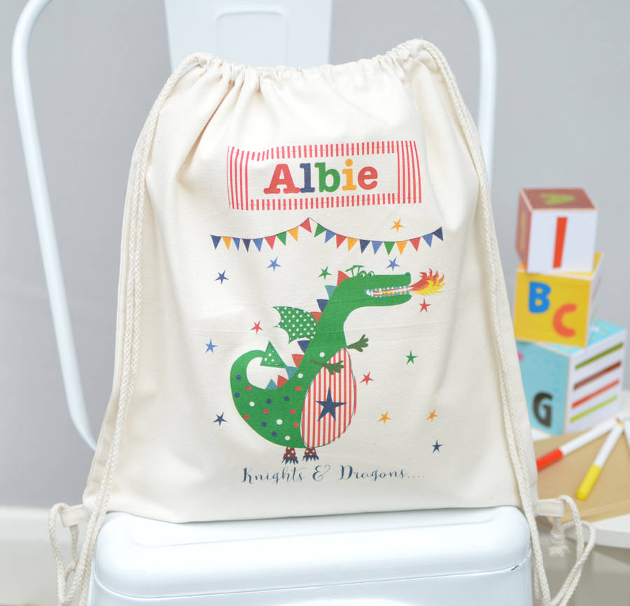 Drawstring bag with a green dragon design and the name 'Albie' on a white chair.