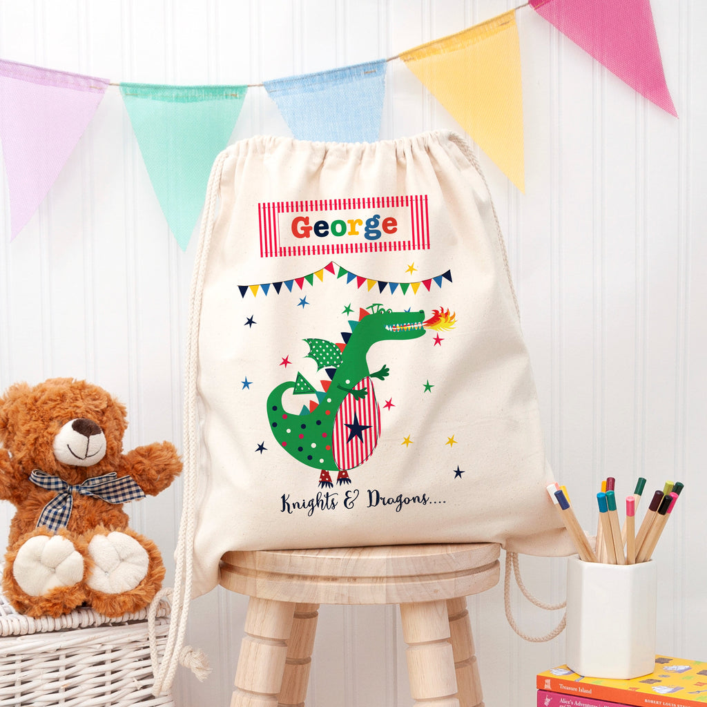 Children's drawstring bag with a dragon design and name 'George' on a wooden stool.