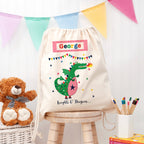 Children's drawstring bag with a dragon design and name 'George' on a wooden stool.