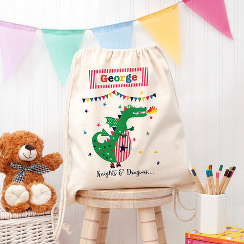 Children's drawstring bag with a dragon design and name 'George' on a wooden stool.