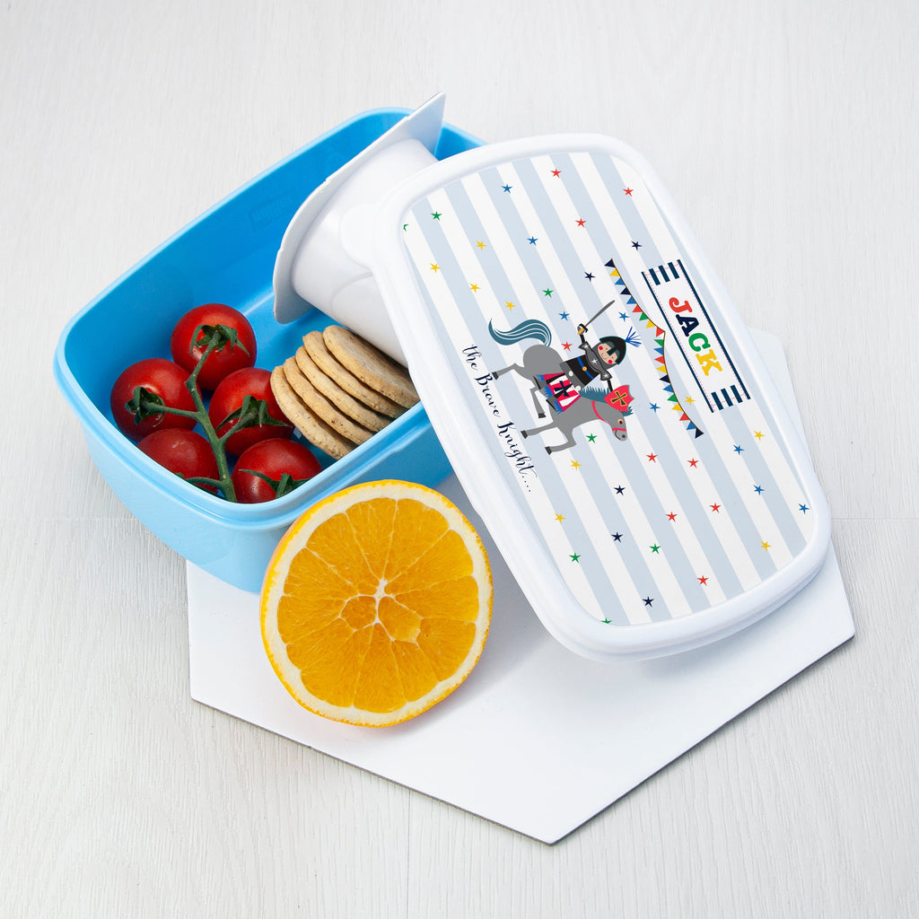 Bento box with colorful design, tomatoes, cookies, and an orange on a white background