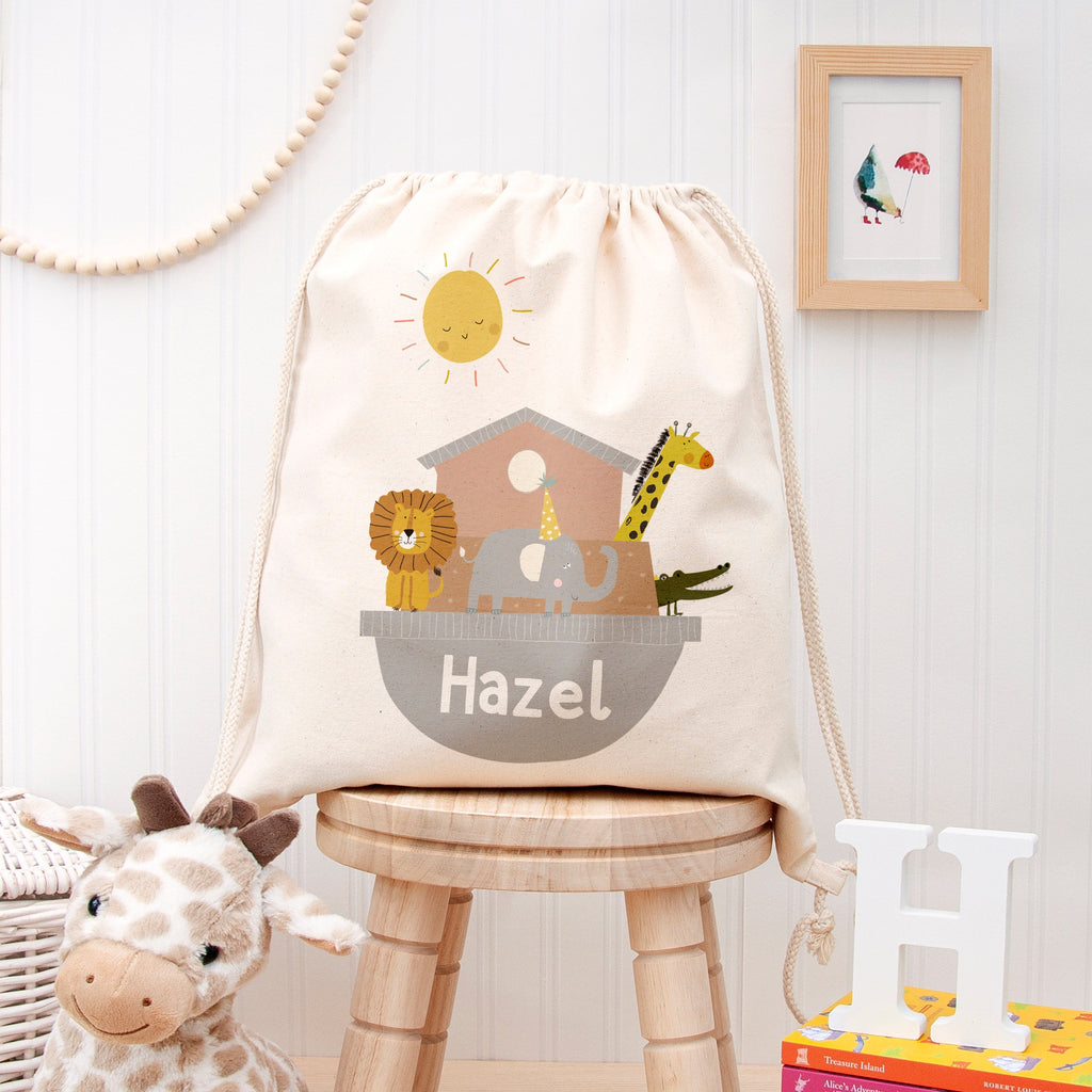 Drawstring bag with animal illustrations and 'Hazel' text on a wooden stool in a child's room.