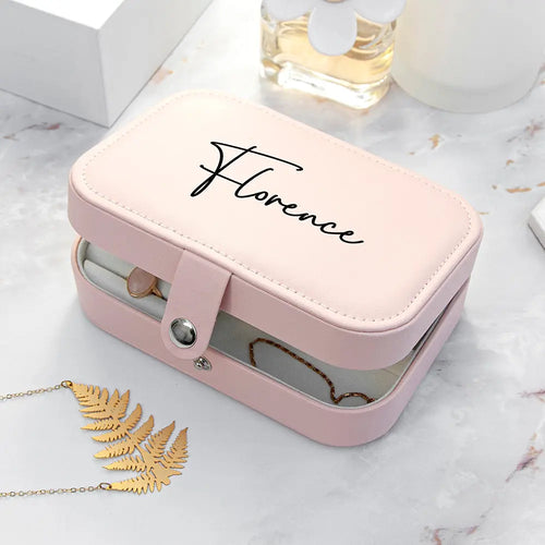 Pink jewelry box with 'Florence' branding on a marble surface with a necklace and leaf decoration.