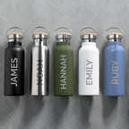 Five insulated water bottles in different colors with names engraved on them, against a gray background.