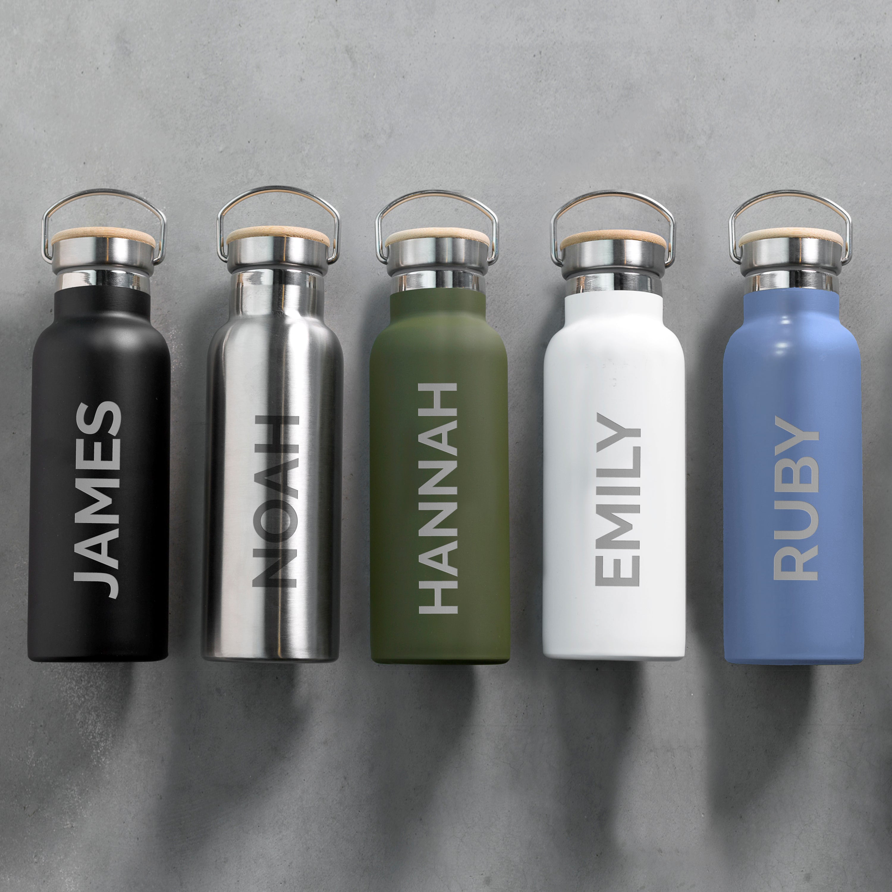 Five insulated water bottles in different colors with names engraved on them, against a gray background.