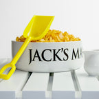 White bowl with 'Jack's Man' text, yellow shovel, and corn on a white background