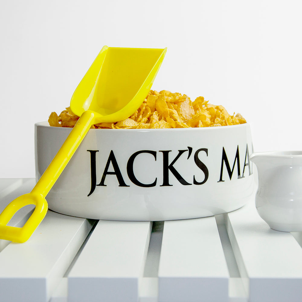 White bowl with 'Jack's Man' text, yellow shovel, and corn on a white background