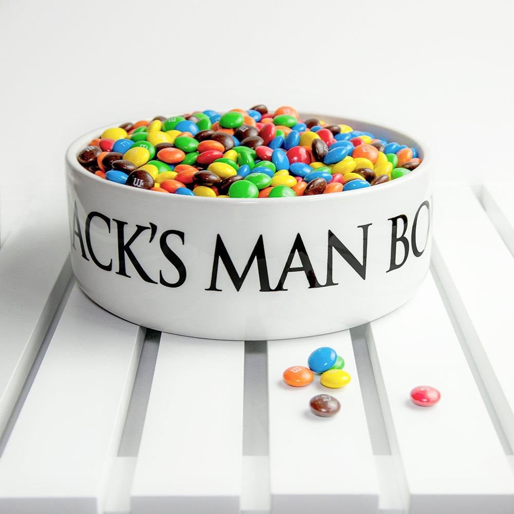 White bowl filled with colorful candies on a white surface