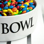 White bowl filled with colorful M&M candies on a white background