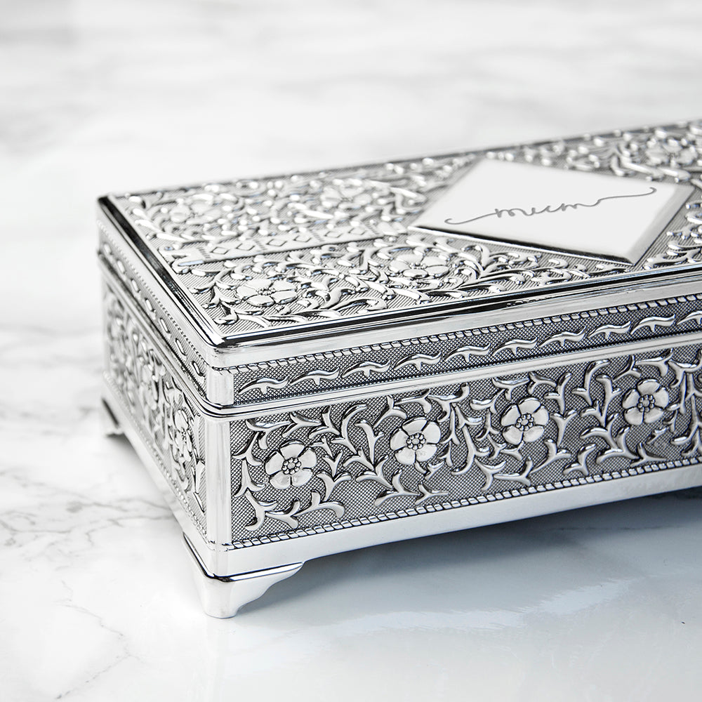 Decorative silver jewelry box with intricate patterns on a marble surface