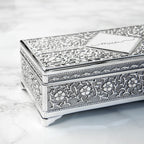 Decorative silver jewelry box with intricate patterns on a marble surface