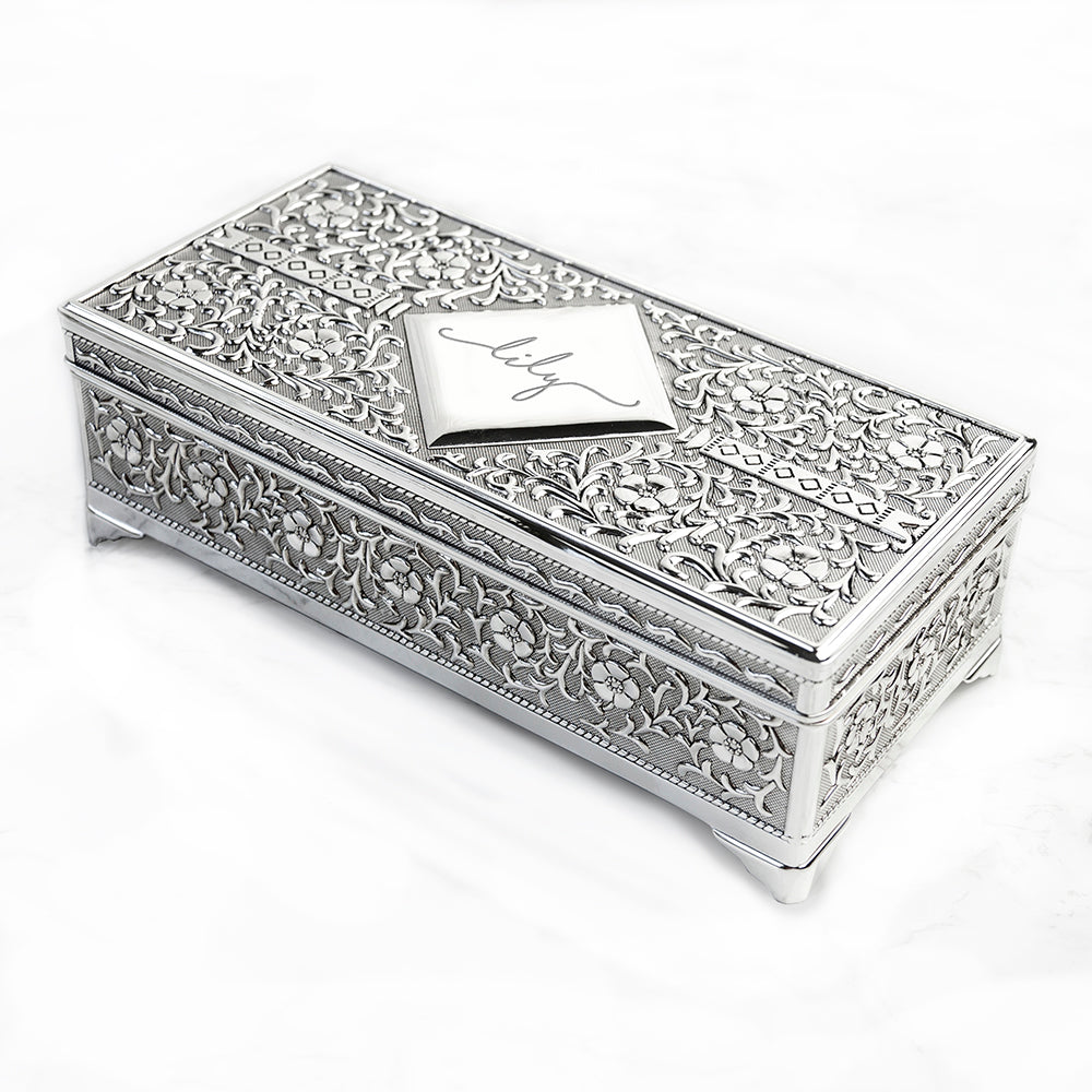 Decorative silver jewelry box with intricate patterns on a white background