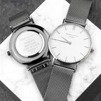 Two watches with mesh straps on a marble surface