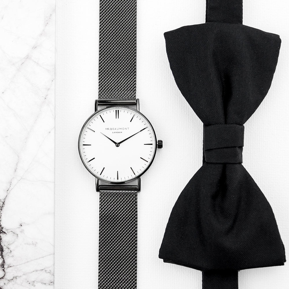 Black watch with mesh band and black bow tie on a white background
