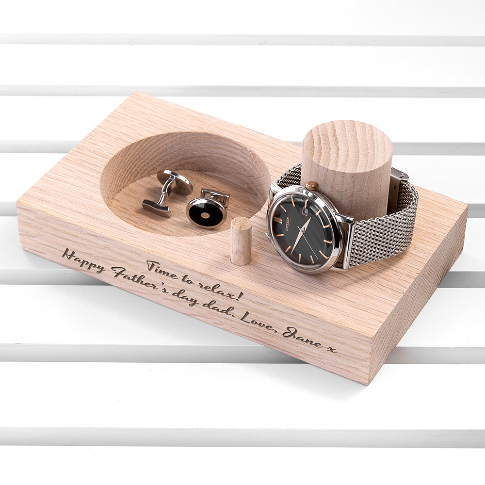 Wooden jewelry display with watch, cufflinks, and a message on a white background