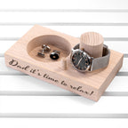 Wooden tray with watch, cufflinks, and engraved message on a white background