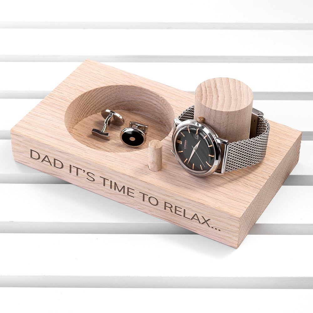 Wooden jewelry display with watch, cufflinks, and a message on a white background