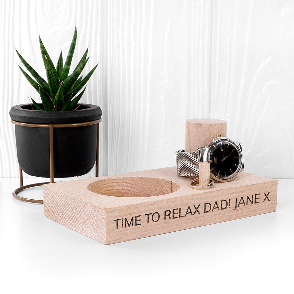 Wooden desk organizer with a watch, candle, and small plant on a white surface.