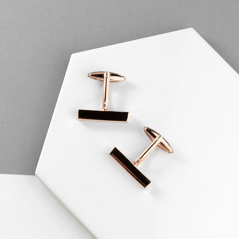 Pair of rose gold and black earrings on a white surface with a gray background