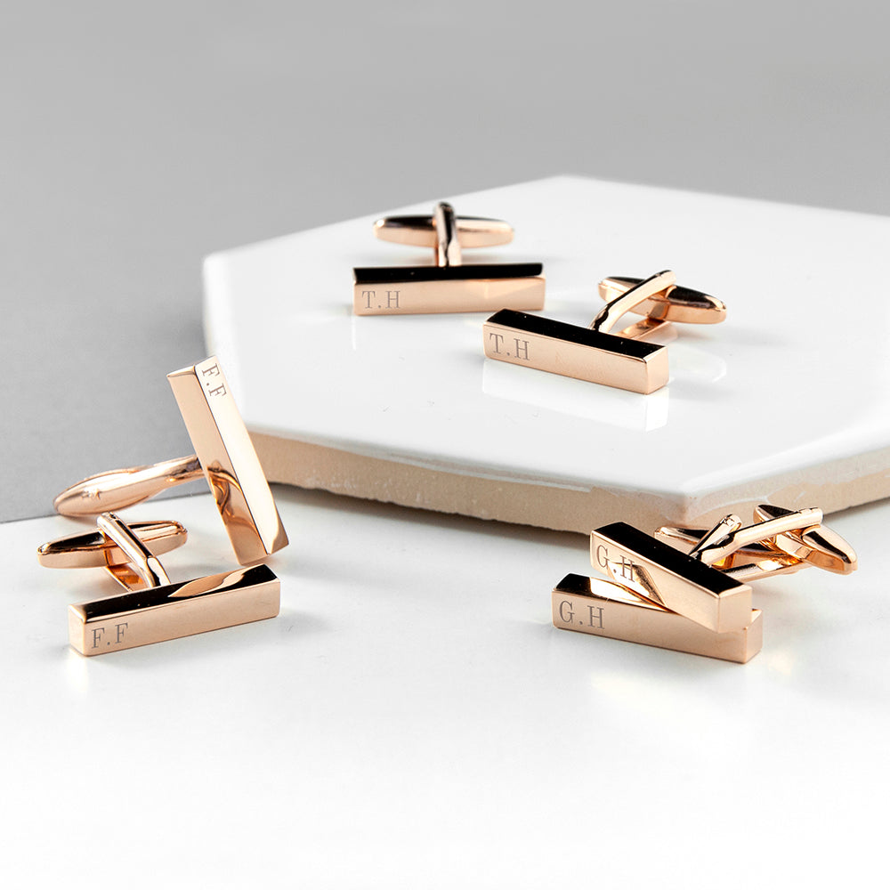 Set of rose gold cufflinks on a white surface with a gray background