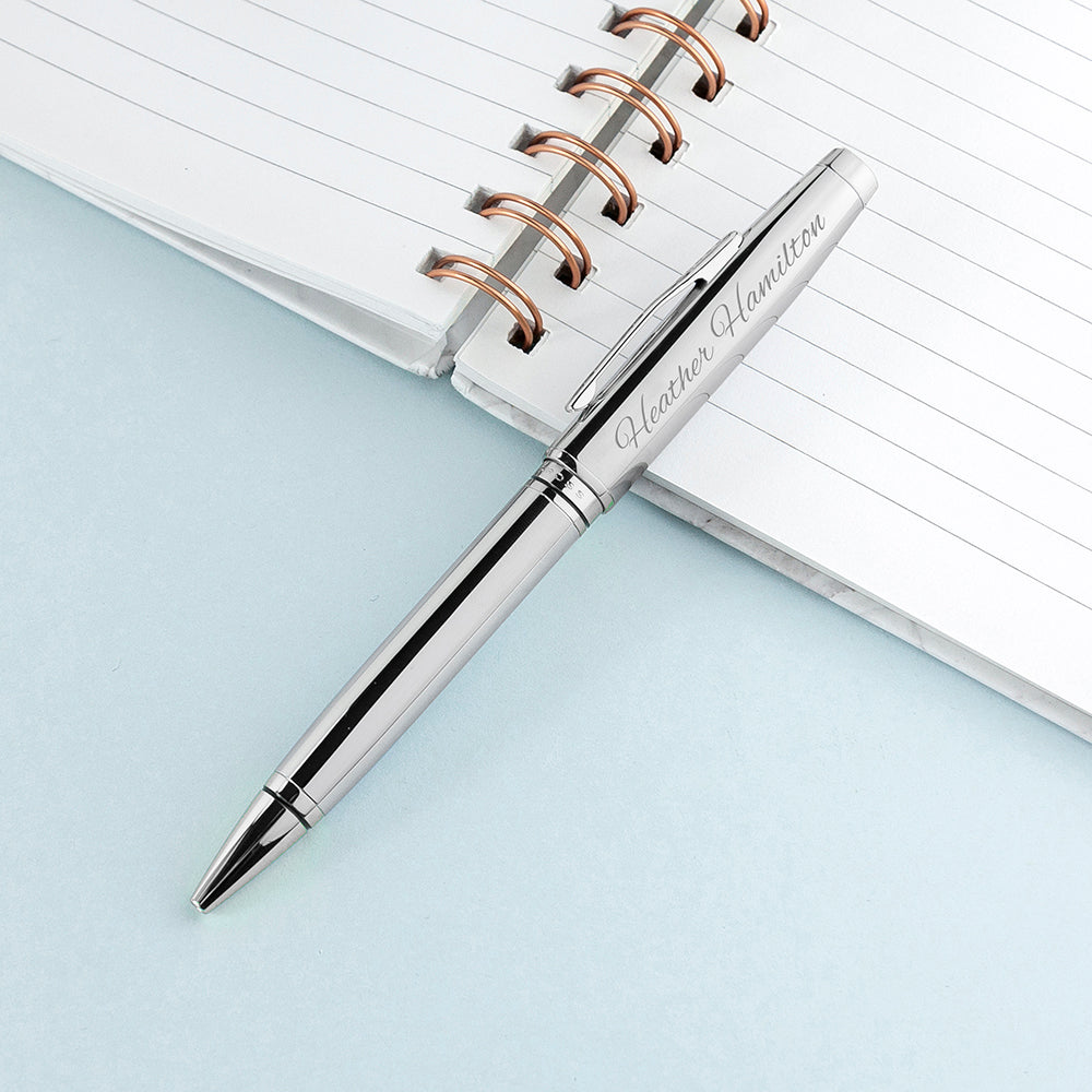 Silver pen with engraved text on a notebook