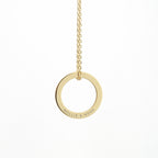 Gold necklace with a circular pendant on a white background