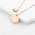 Rose gold necklace with engraved pendant on a white surface