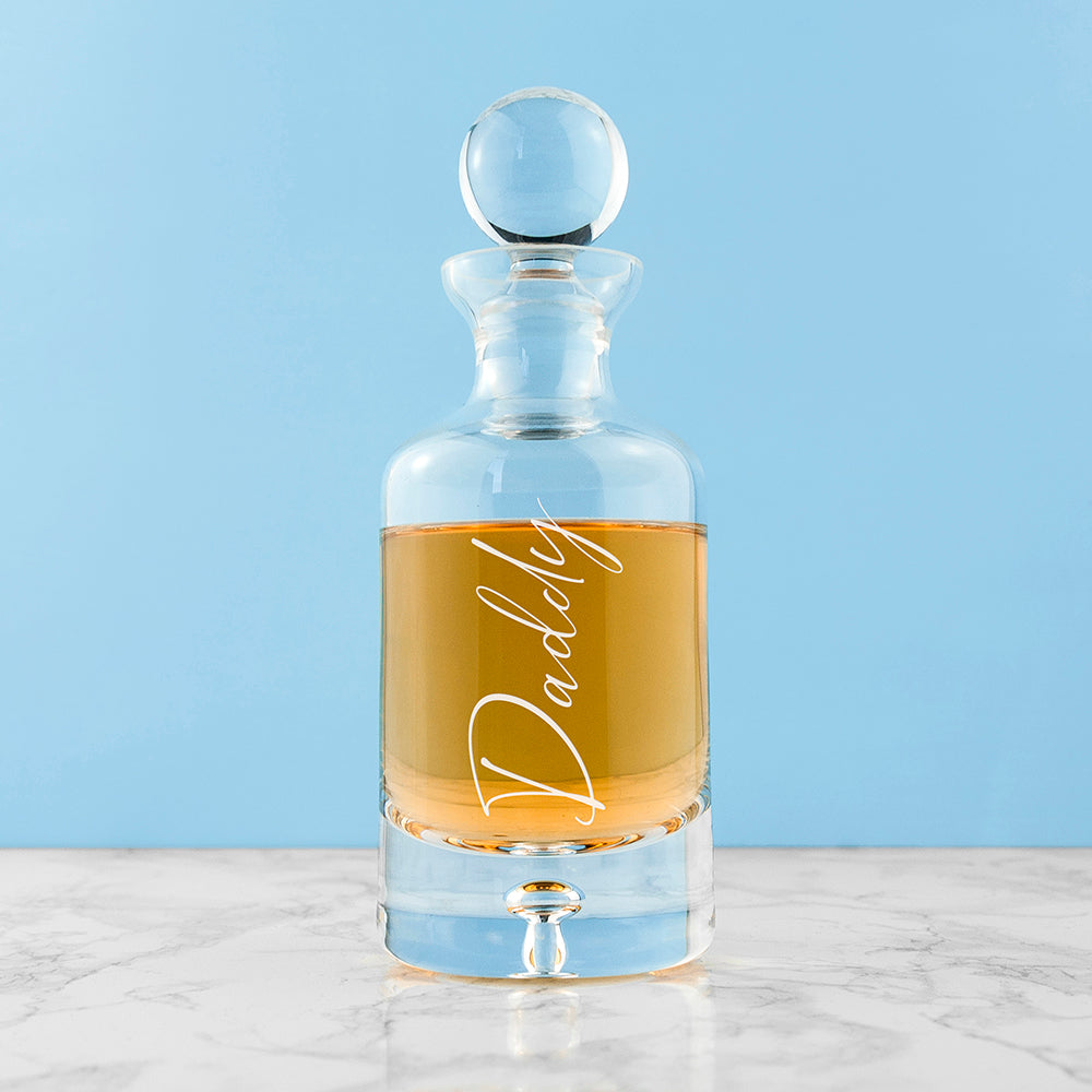 Glass decanter with 'Daddy' engraving on a light blue background