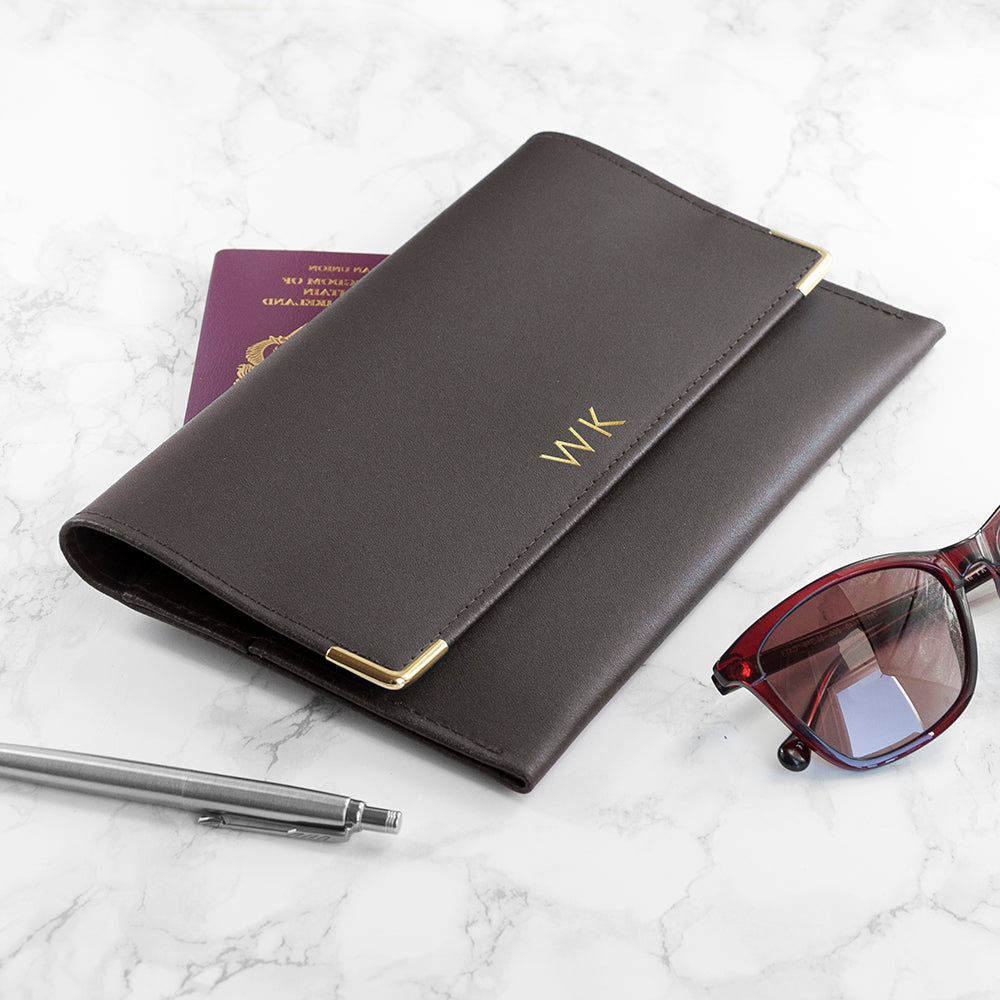 Black leather wallet with gold accents, sunglasses, and pen on a marble surface