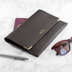 Black leather wallet with gold accents, sunglasses, and pen on a marble surface