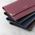 Set of four leather wallets in different colors on a light gray surface