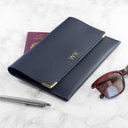 Navy leather wallet with gold accents, sunglasses, and pen on a marble surface