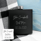 Black flask with engraved text on a checkered fabric background