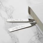 Two silver hair straighteners with engraved text on a marble surface