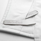 Two silver hair clips with engraved text on a white textured background