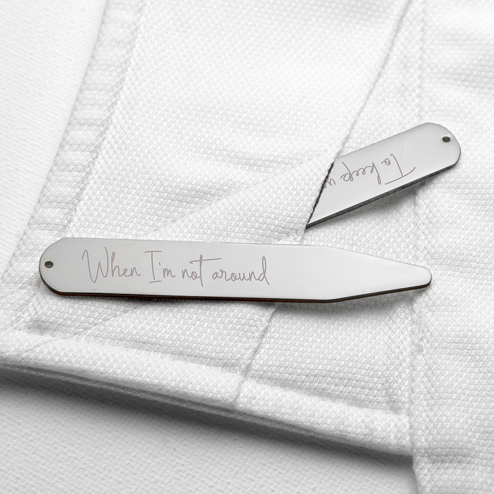 Two silver hair clips with engraved text on a white textured background
