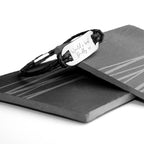 Black braided bracelet with engraved message on a black card